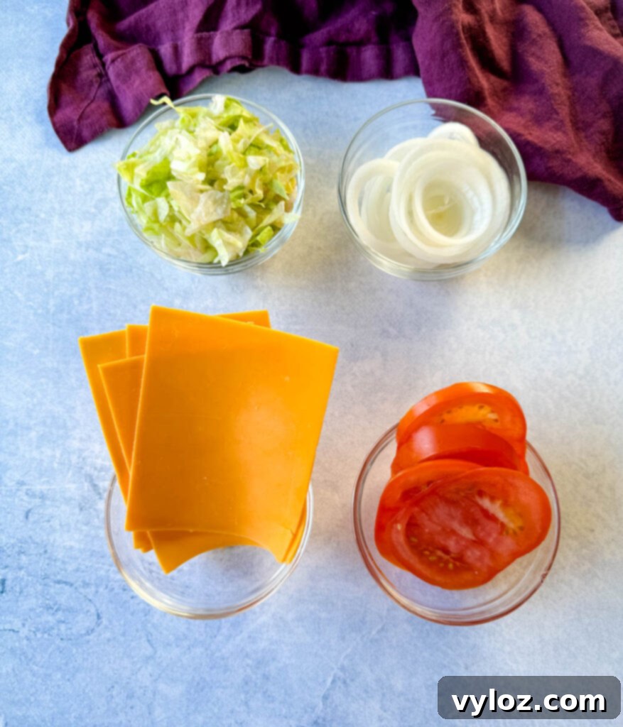shredded lettuce, sliced onions, sliced cheese, and sliced tomatoes in separate glass bowls