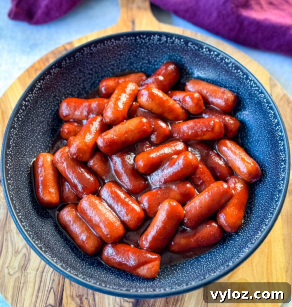 Sweet and Sticky BBQ Little Smokies 9 little smokies and BBQ sauce in a black bowl with a toothpick