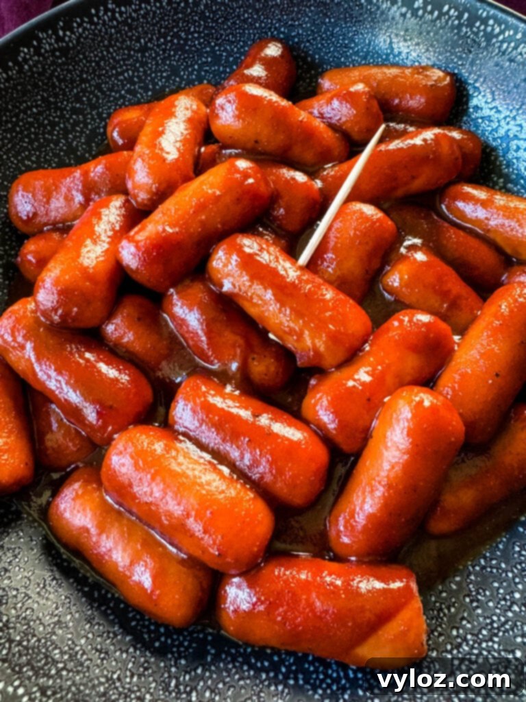 Sweet and Sticky BBQ Little Smokies 10 little smokies and BBQ sauce in a black bowl with a toothpick