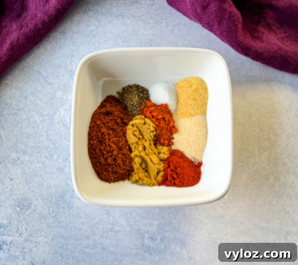 A small white bowl filled with a vibrant blend of homemade taco seasoning spices, including chili powder, cumin, and paprika.