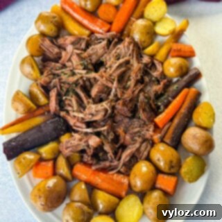 Melt-in-Your-Mouth Slow Cooker Beef Roast 15 cooked beef pot roast, carrots, and potatoes on a white plate