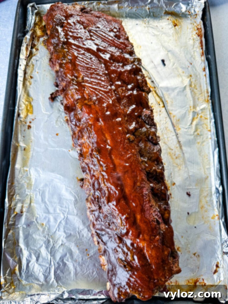 Fall-Off-The-Bone Oven Baby Back Ribs 8 oven baked ribs on foil with BBQ sauce