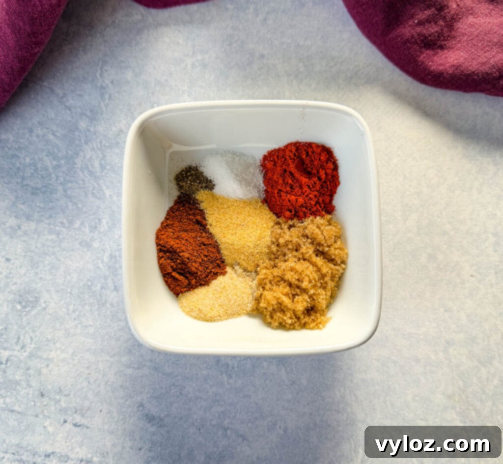 Close-up of various spices for rib dry rub in a white bowl, showcasing their vibrant colors and textures