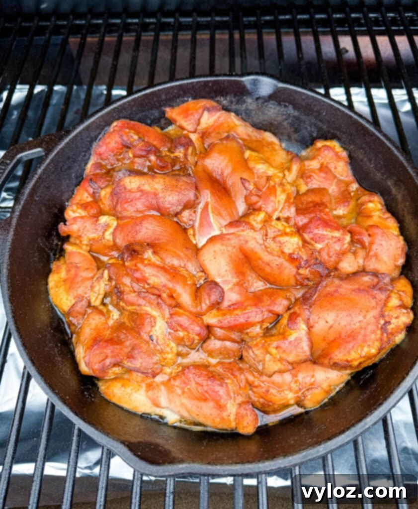 Smoky Traeger Pulled Chicken 7 raw chicken thighs in a cast iron skillet on a Traeger pellet grill smoker