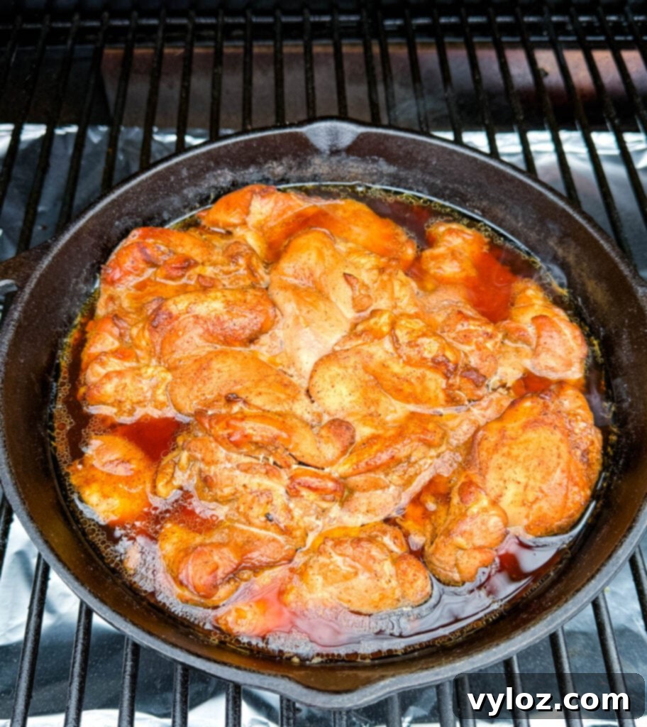 Smoky Traeger Pulled Chicken 9 smoked pulled chicken thighs in a cast iron skillet on a Traeger pellet grill smoker