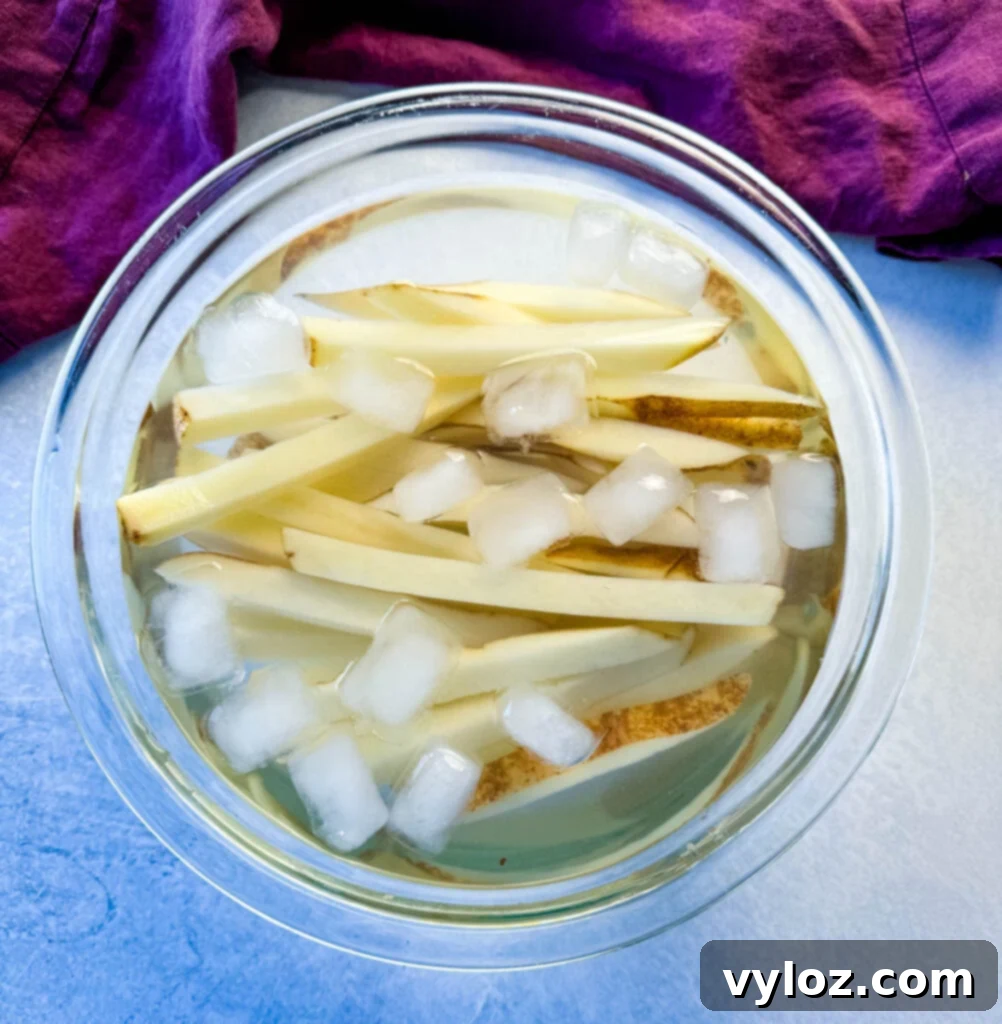 Cajun Seasoned Fries 5 sliced potatoes with water and ice in a glass bowl