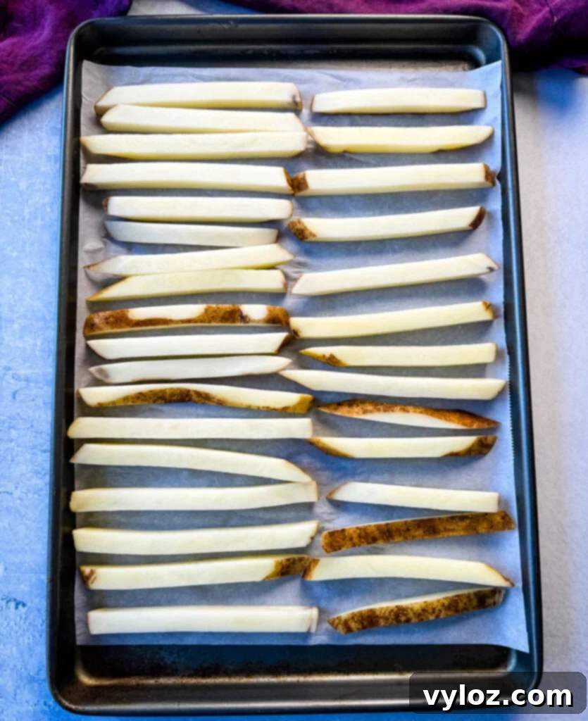 Cajun Seasoned Fries 8 sliced potatoes on a sheet pan with parchment paper