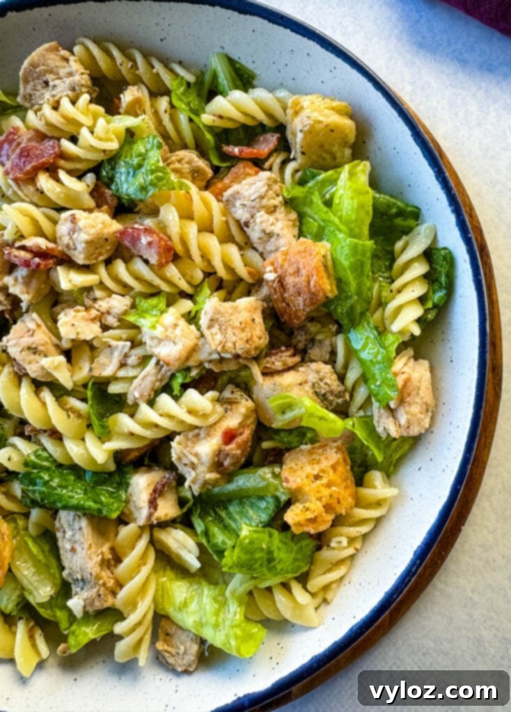 Chicken Caesar Pasta Salad with bacon and croutons in a white bowl