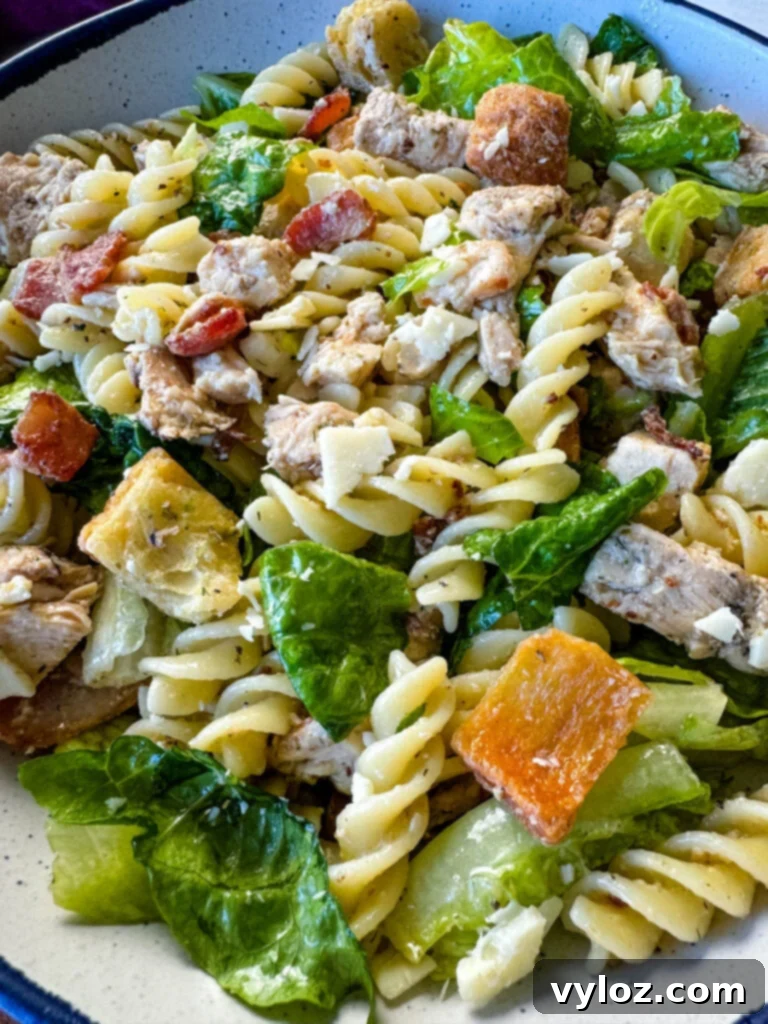 Chicken Caesar Pasta Salad with bacon and croutons in a white bowl