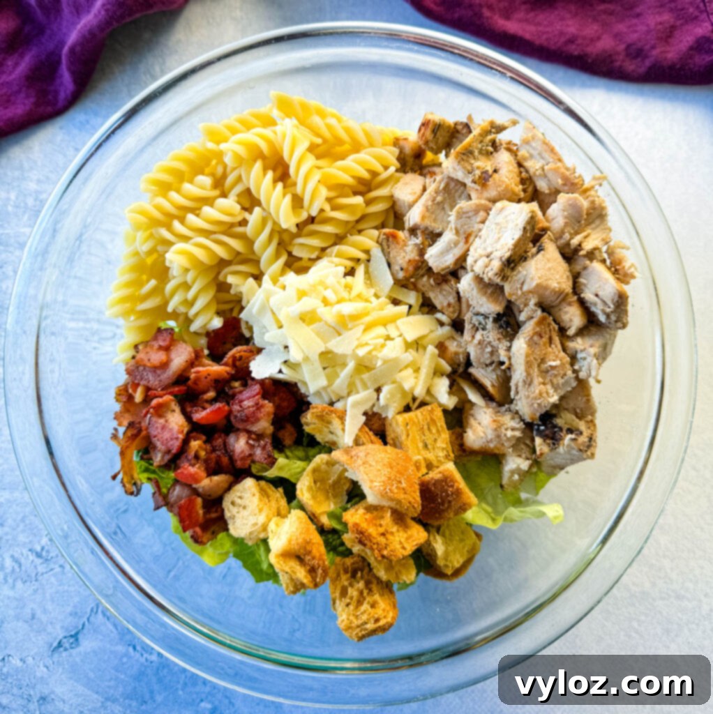 Chicken Caesar Pasta Salad with bacon and croutons in a glass bowl