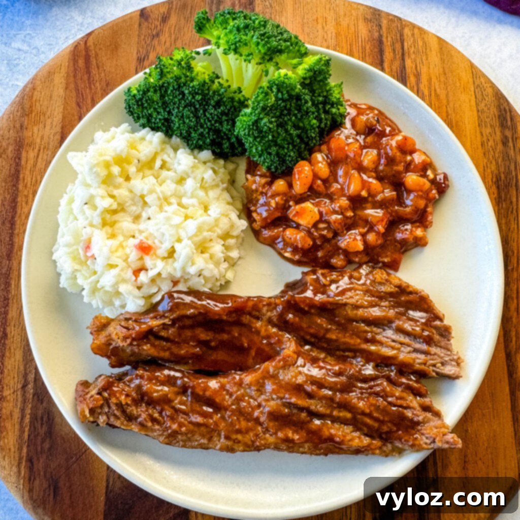 slow cooker Crockpot beef brisket with BBQ sauce on a plate with beans, broccoli, and coleslaw
