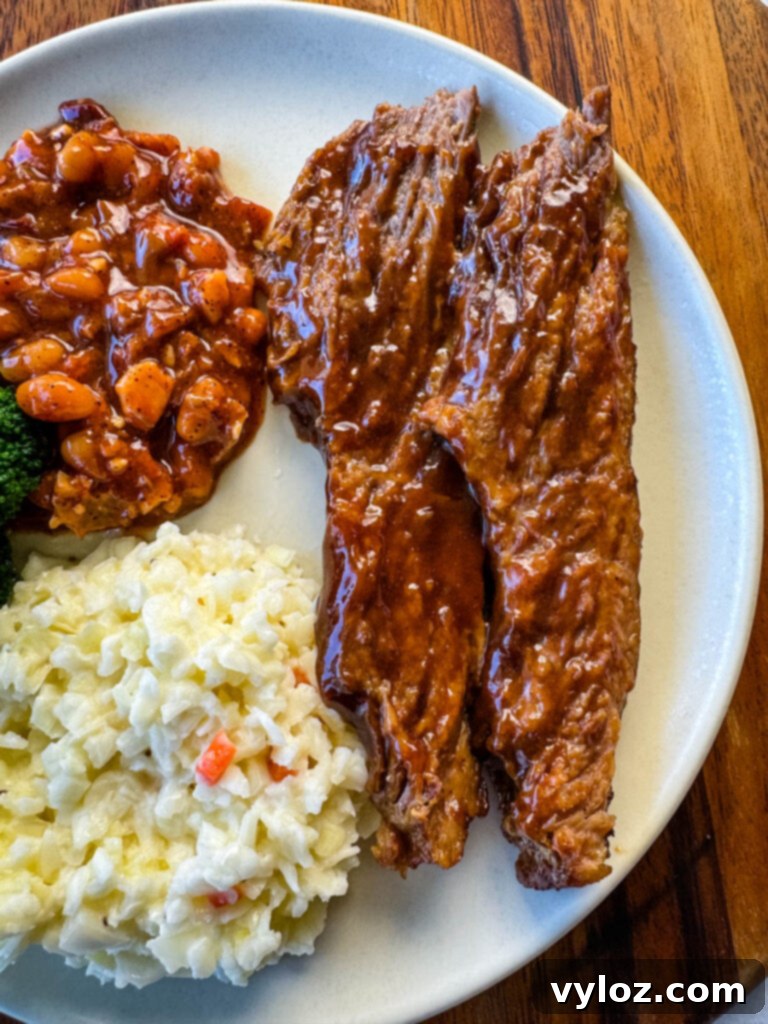 slow cooker Crockpot beef brisket with BBQ sauce on a plate with beans and coleslaw