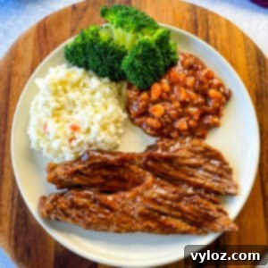 slow cooker Crockpot beef brisket with BBQ sauce on a plate with beans, broccoli, and coleslaw