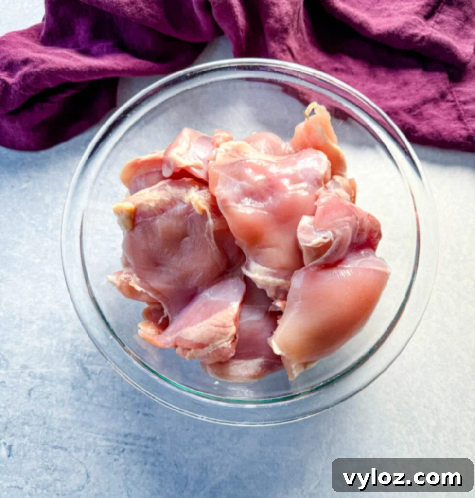 Savory Grilled Chicken Rub 3 Raw chicken thighs ready for seasoning in a clear glass bowl, showcasing their fresh appearance.