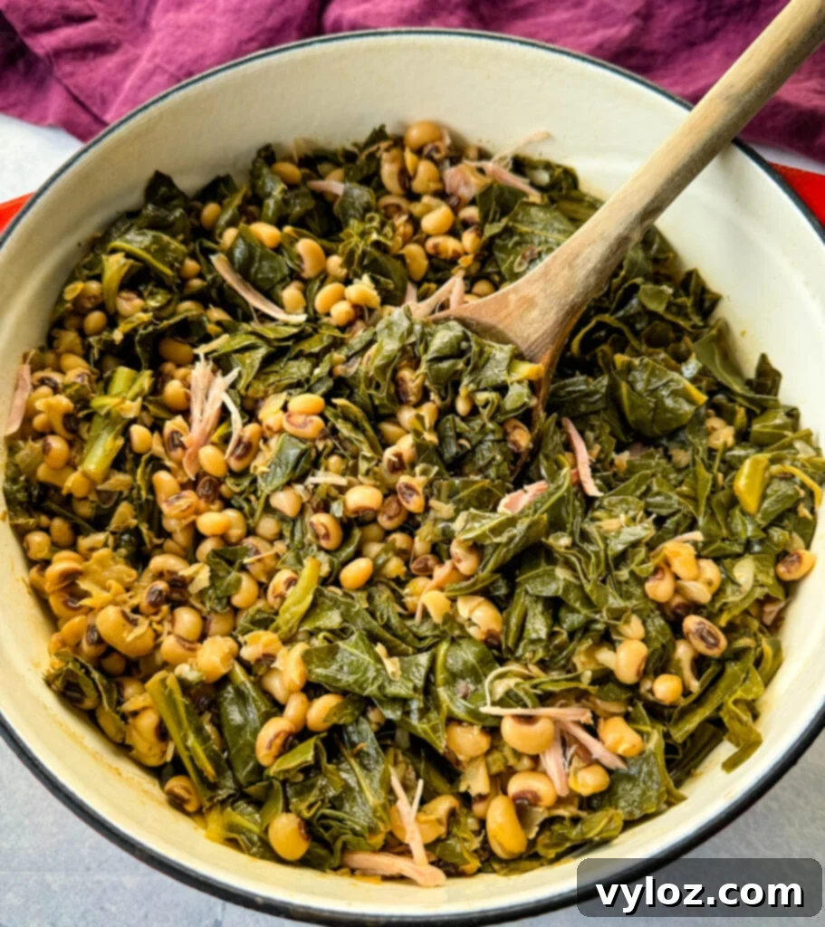 A vibrant red Dutch oven filled with rich, smoky collard greens and black-eyed peas, accompanied by a wooden spoon, ready to be served.