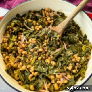 collard greens and black eyed peas with smoked turkey in a red Dutch oven with a wooden spoon