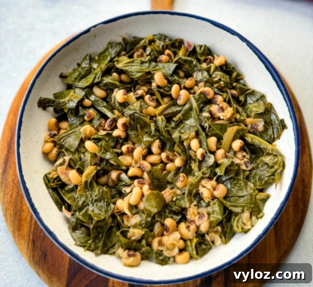 A serving of collard greens and black-eyed peas, glistening with flavorful pot liquor, in a rustic white bowl, ready to be enjoyed.