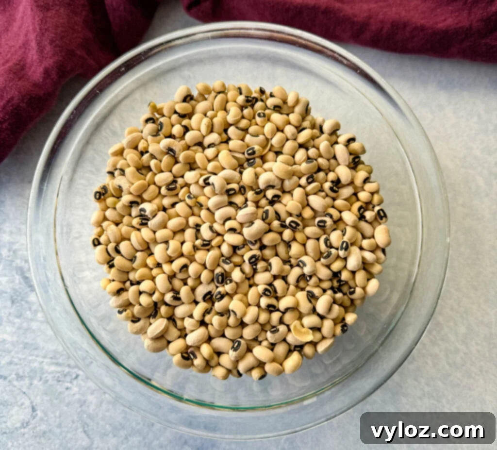 A clear glass bowl filled with dry black-eyed peas, showcasing their distinct color and shape before cooking.