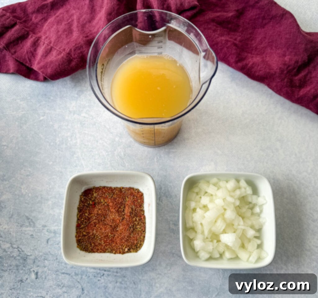 Three white bowls containing essential recipe components: flavorful broth, a blend of aromatic spices, and finely diced onions, ready for cooking.