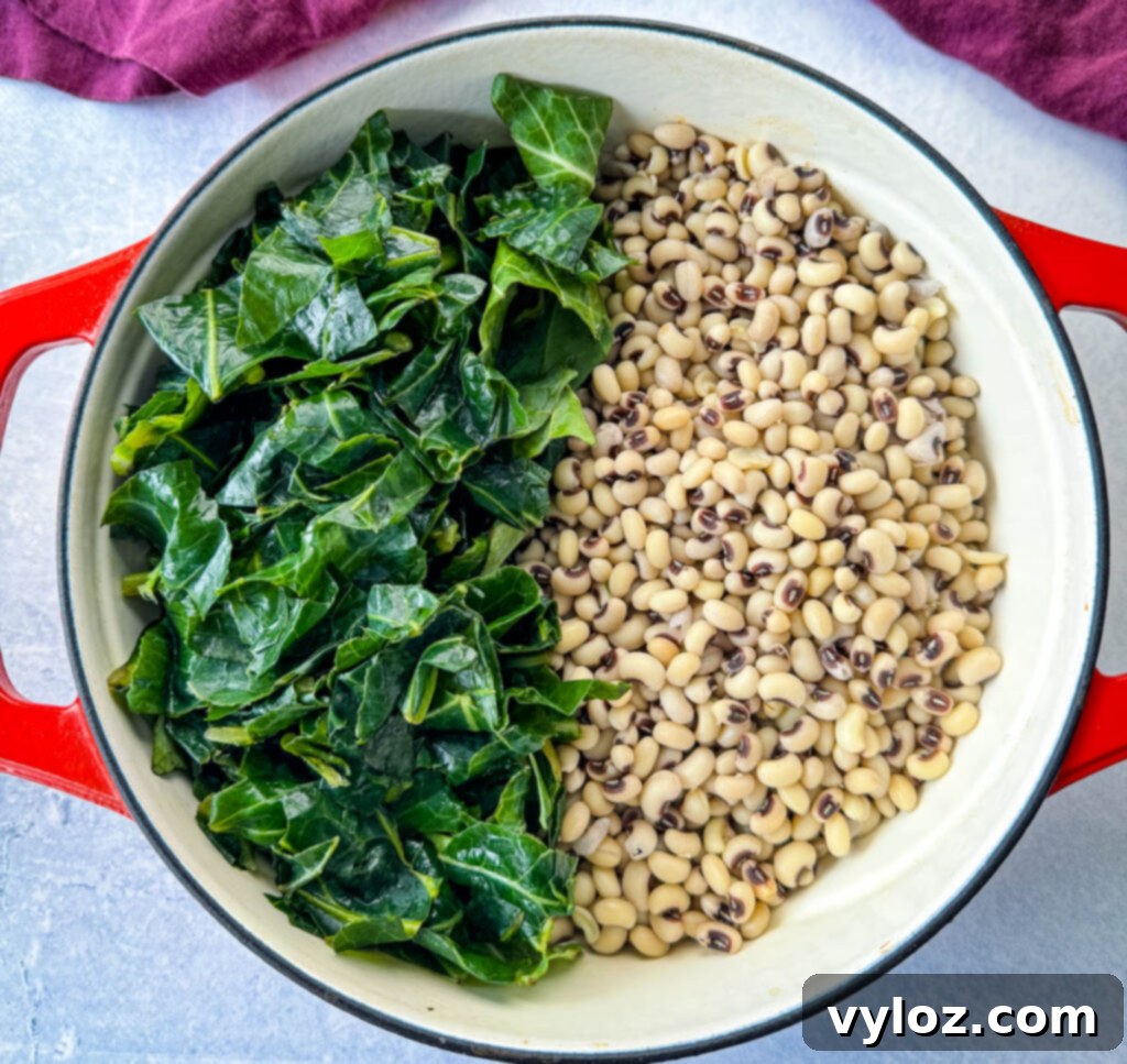 Uncooked collard greens and black-eyed peas, with chunks of smoked turkey, nestled in a red Dutch oven before simmering.