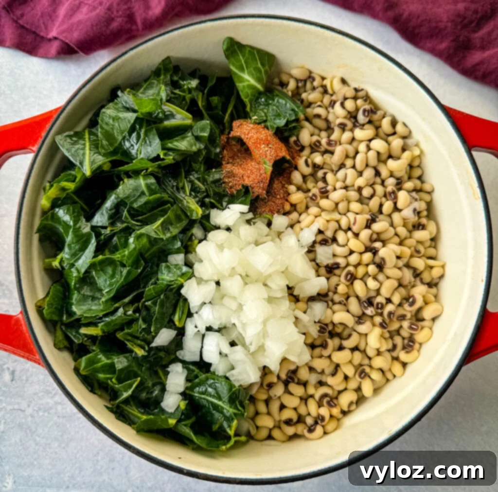 A closer view of uncooked collard greens and black-eyed peas, combined with smoked turkey in a red Dutch oven, ready for the cooking process.