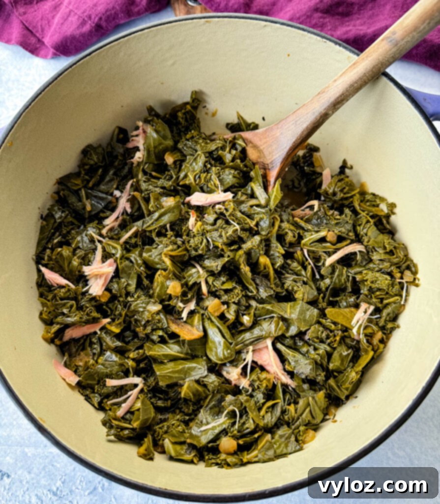 Southern Mixed Greens Medley 11 Mixed collard, turnip, mustard greens, and kale in a Dutch oven with a wooden spoon, indicating it's ready to be served or stirred.