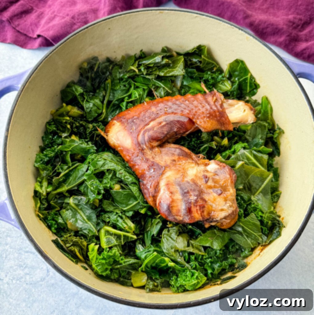 Southern Mixed Greens Medley 7 A Dutch oven filled with uncooked mixed greens and a smoked turkey leg, beginning the cooking process.