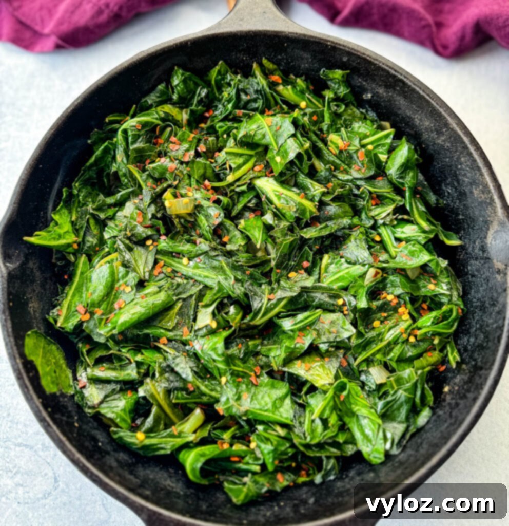 Sautéed collard greens with crushed red pepper in a cast iron skillet, bubbling and fragrant.