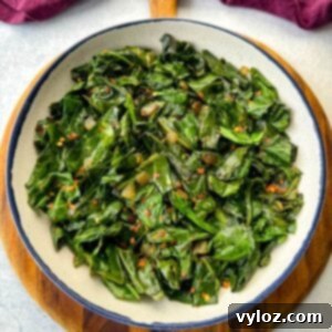 Sautéed collard greens with crushed red pepper in a white bowl, garnished and ready.