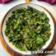 Sauteed collard greens with crushed red pepper in a white bowl.