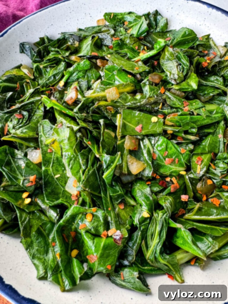 A generous serving of sautéed collard greens with crushed red pepper in a white bowl, ready to enjoy.