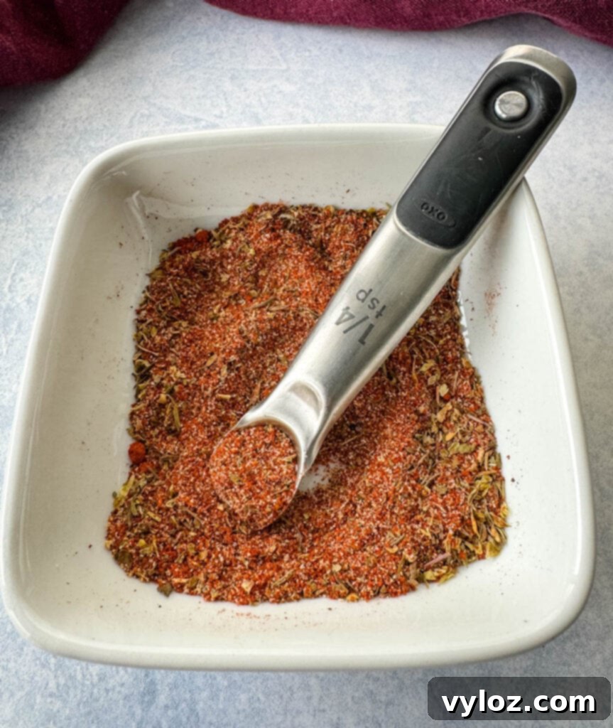 collard greens seasoning dry spices in a white bowl with a measuring spoon, highlighting the texture and color of the homemade blend
