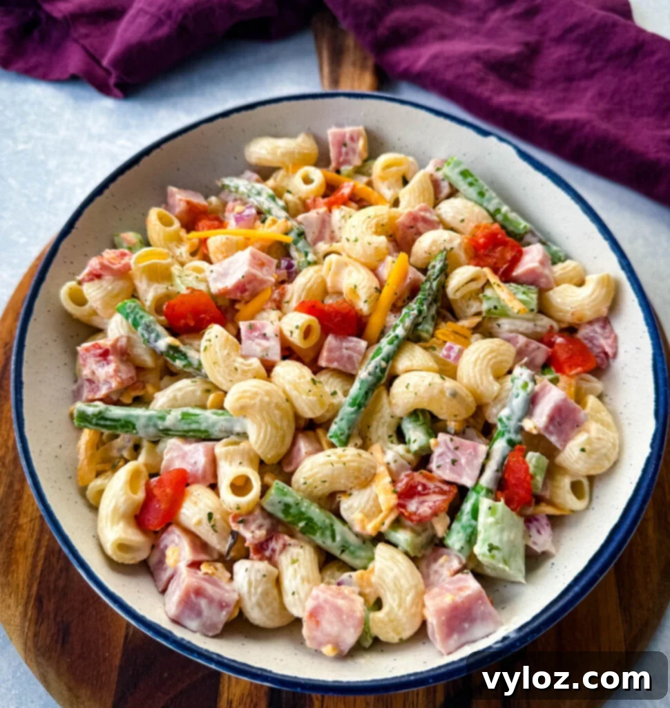 Classic Ham Pasta Salad 2 ham pasta salad with cheese, asparagus and tomatoes in a white bowl