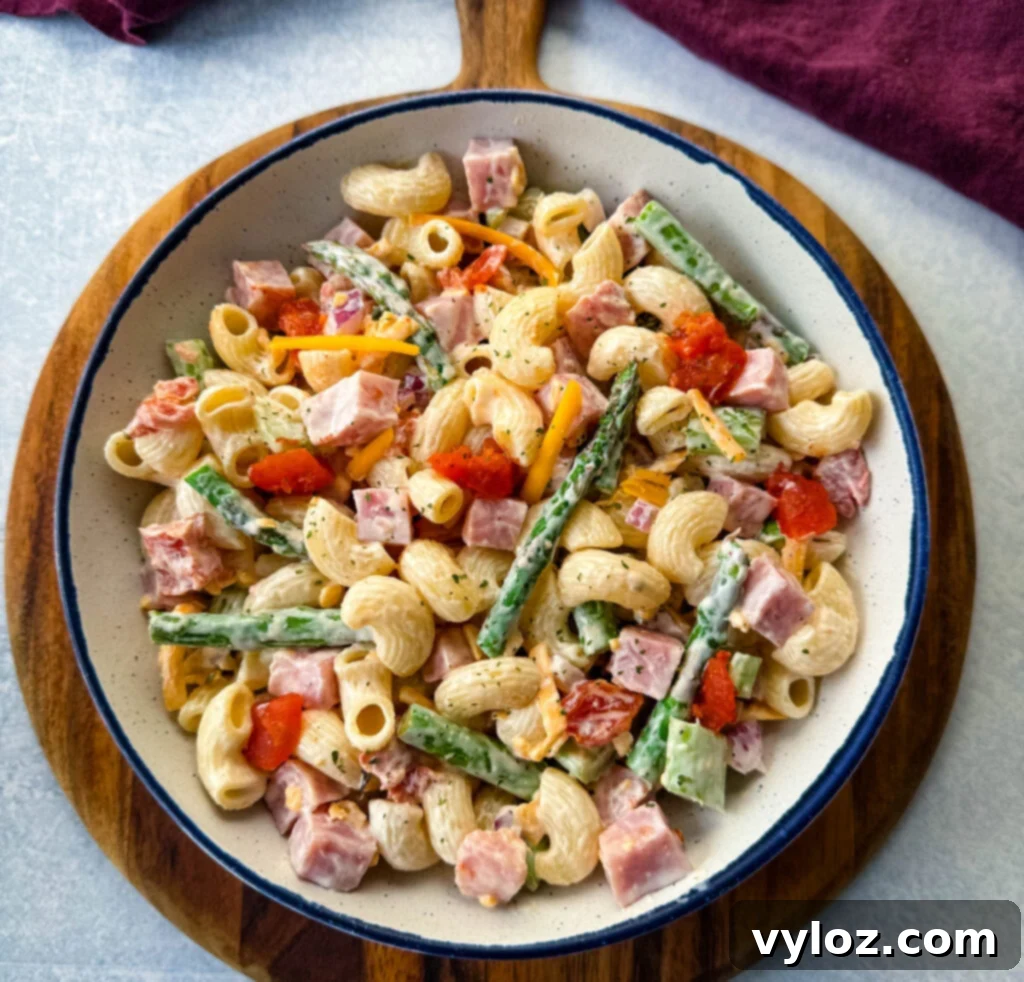 Classic Ham Pasta Salad 11 ham pasta salad with cheese, asparagus and tomatoes in a white bowl
