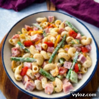 Classic Ham Pasta Salad 13 ham pasta salad with cheese, asparagus and tomatoes in a white bowl