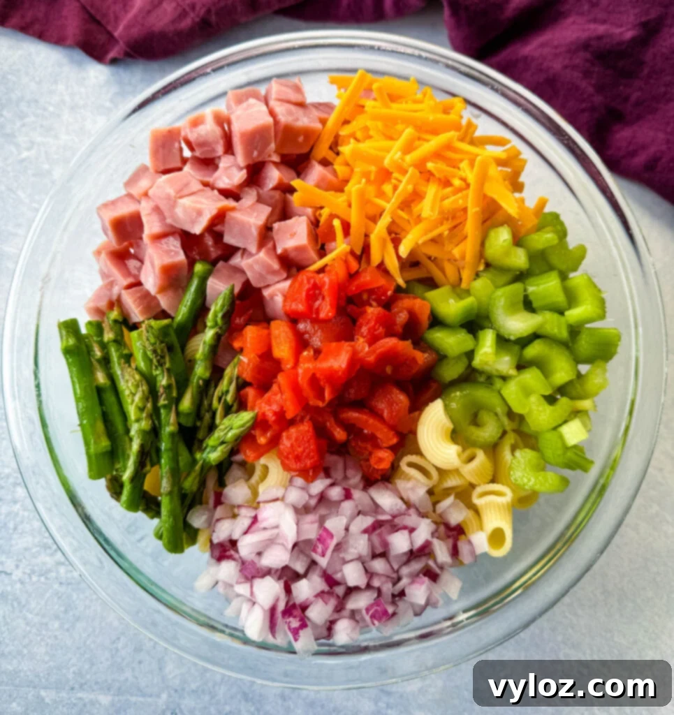 Classic Ham Pasta Salad 9 ham pasta salad with cheese, asparagus and tomatoes in a glass bowl