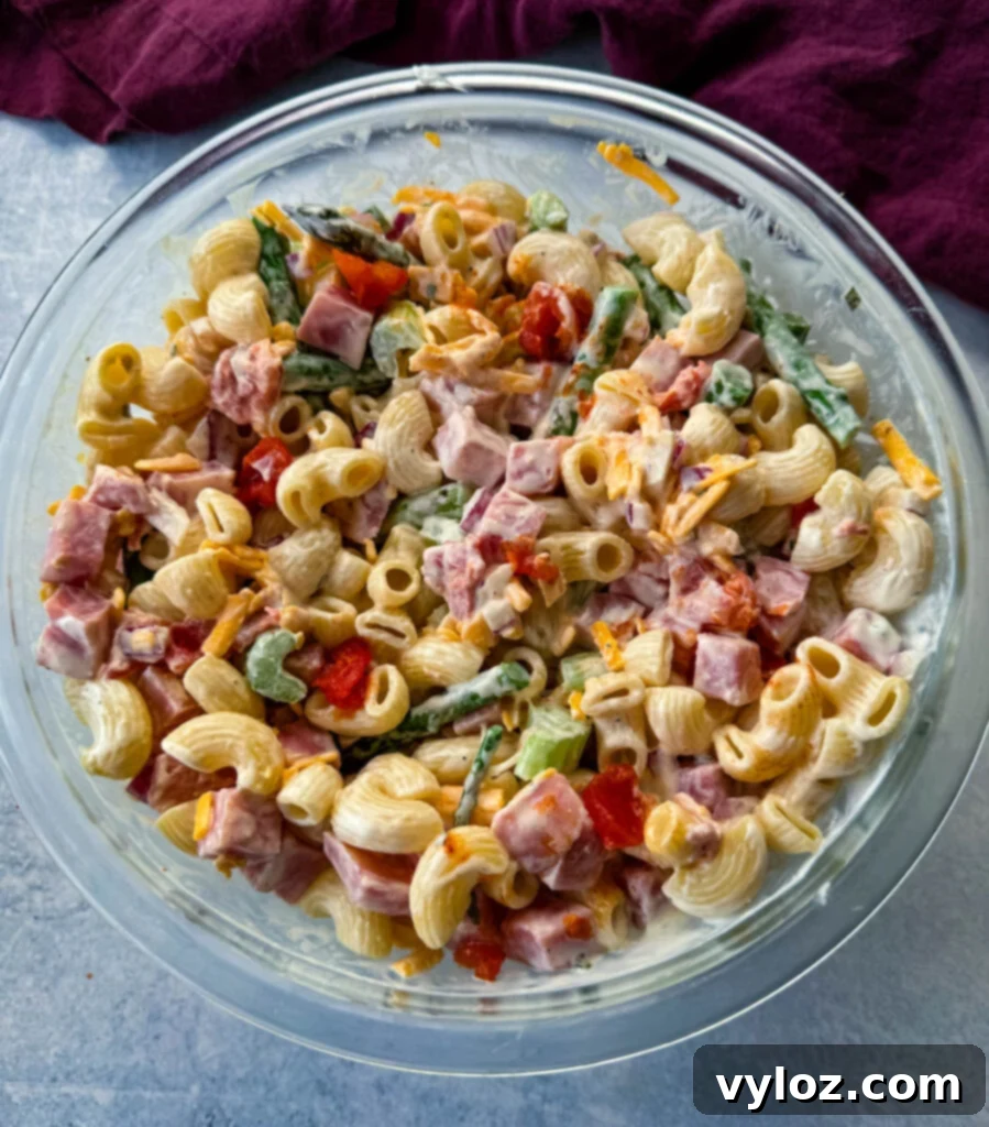 Classic Ham Pasta Salad 10 ham pasta salad with cheese, asparagus and tomatoes in a glass bowl