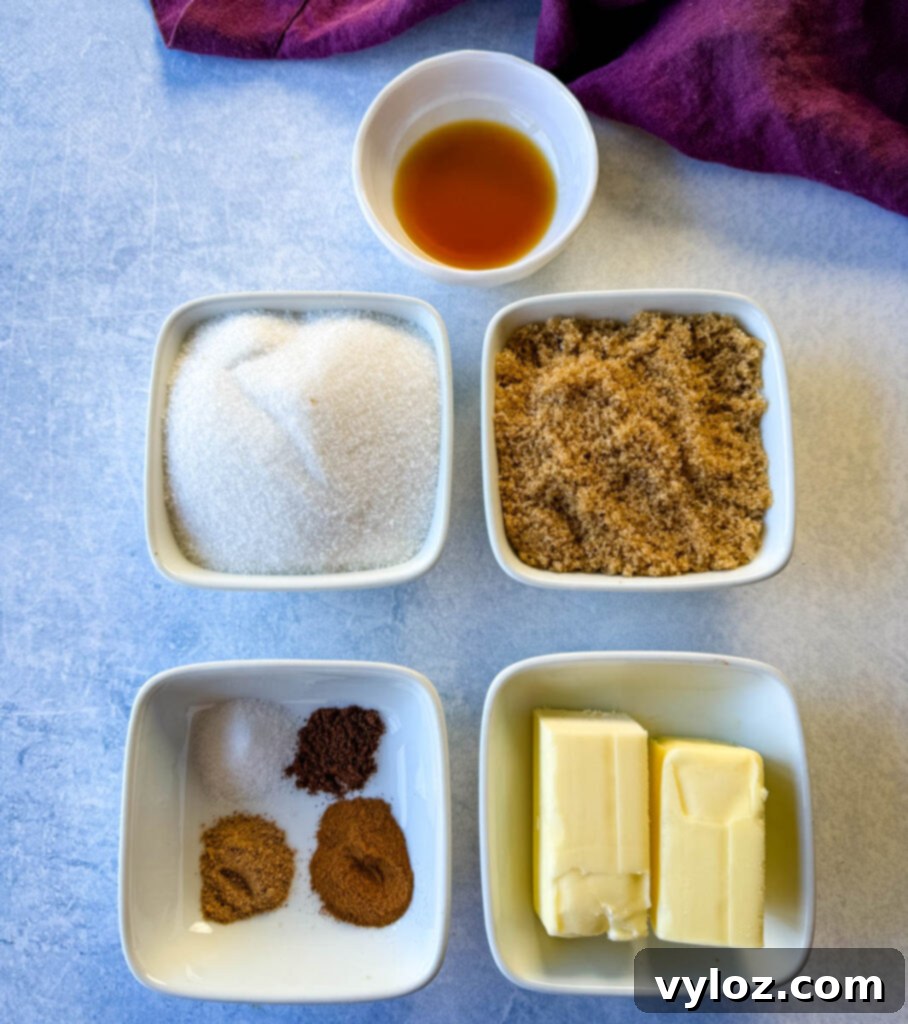 Individual white bowls showcasing ground cinnamon, nutmeg, cloves, white sugar, brown sugar, butter, and vanilla extract, ready for baking.