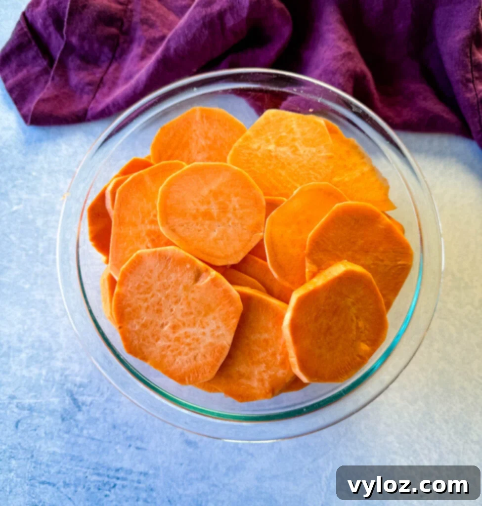 Sweet potatoes, peeled and uniformly sliced into rounds, arranged in a clear glass bowl, ready for the candied glaze.