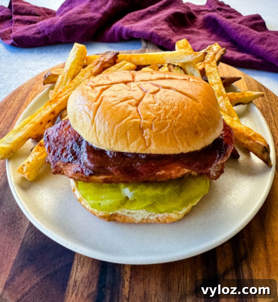 baked bbq chicken breast sandwich with fries on a platte