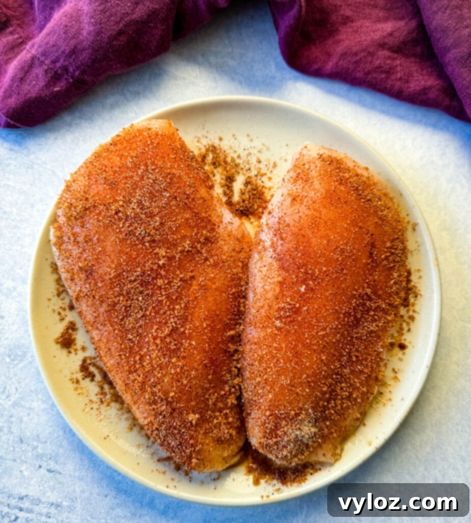 2 seasoned raw chicken breasts on a plate