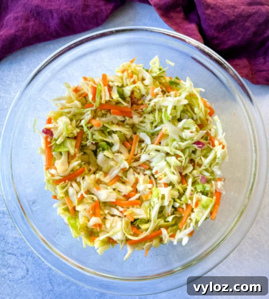 Another view of the fresh vinegar coleslaw in a glass bowl, highlighting its vibrant colors and texture