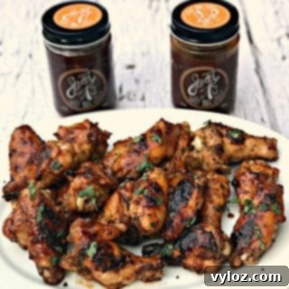 Charred BBQ Ranch Chicken Wings 8 BBQ Ranch Grilled Chicken Wings on a platter with two jars of BBQ sauce in the background.