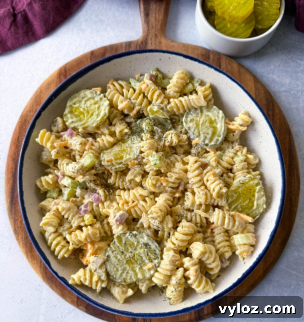 Zingy Dill Pasta Salad 9 A close-up shot of a creamy dill pickle pasta salad in a white bowl, showcasing the chopped pickles and pasta texture.