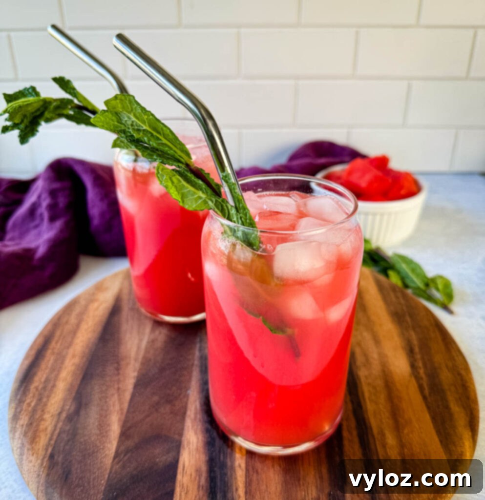 Vibrant watermelon water in a glass, garnished with fresh mint and ice cubes, ready to be enjoyed.