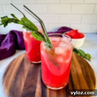 Refreshing watermelon water in a glass, garnished with fresh mint and ice cubes.