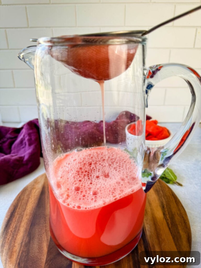 Pureed watermelon being strained into a pitcher, showing the final step before serving.