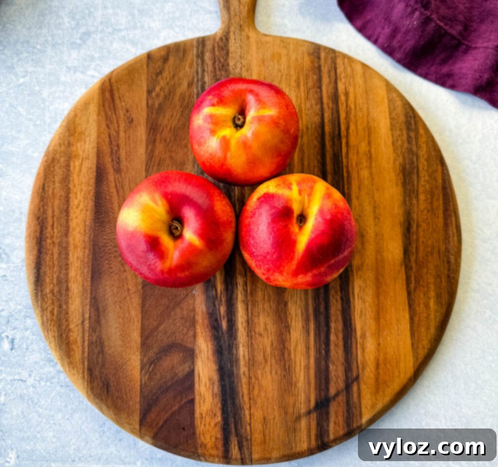 Fresh, ripe peaches arranged on a rustic wooden surface