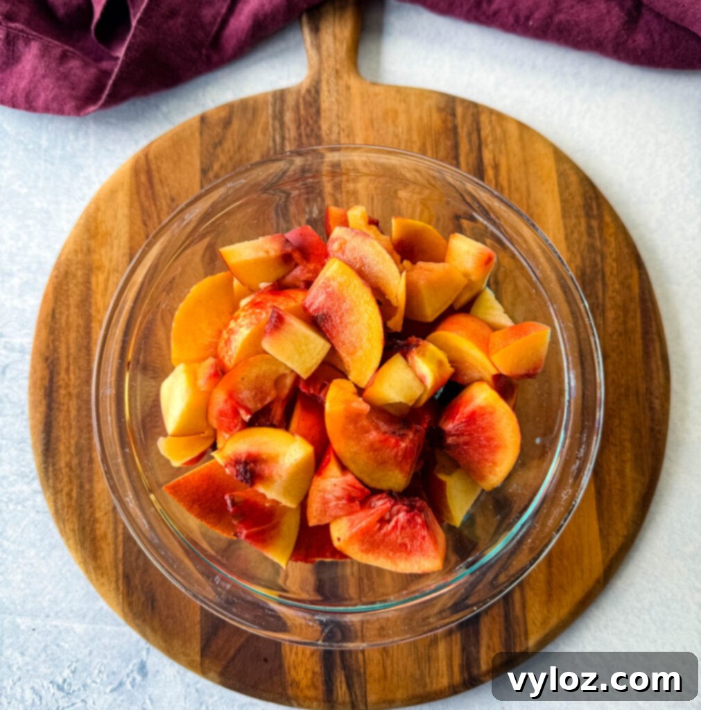 A glass bowl filled with freshly sliced, ripe peaches