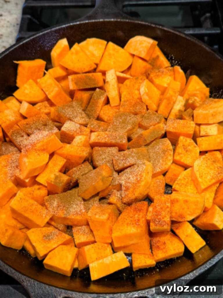 Uncooked, seasoned sweet potato slices arranged in a cast iron skillet, ready for frying.